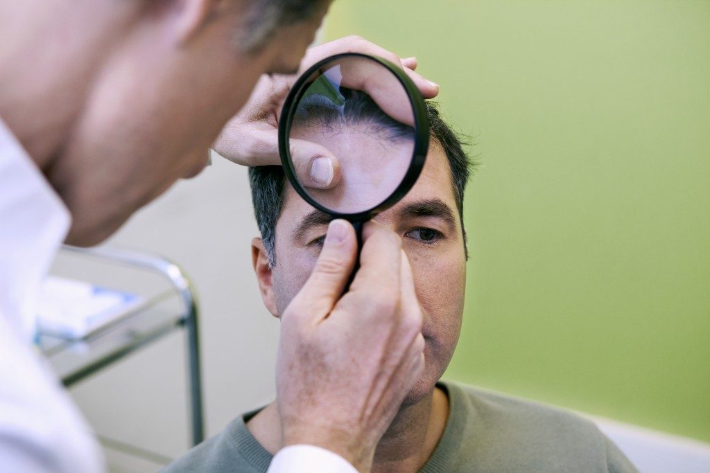 Doctor checking a man's hairline
