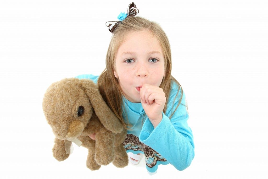Girl holding a stuffed toy while sucking thumb