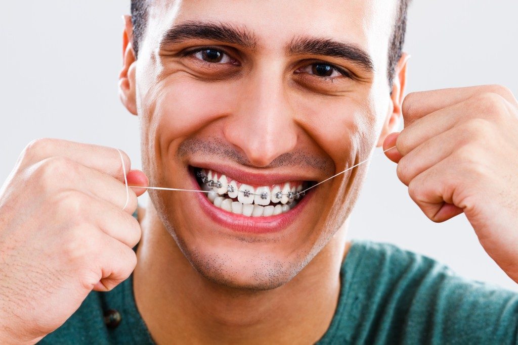 Man with braces flossing