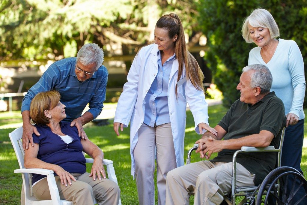 seniors relaxing in a park of a nursing home with geriatric nurse
