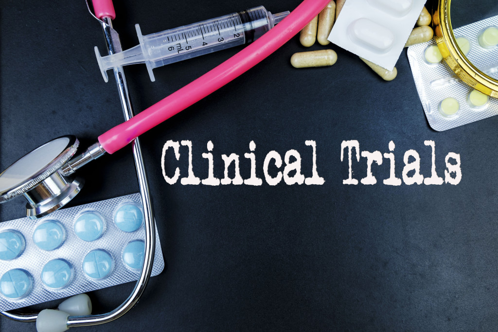 stethoscope and some medicine in the table and a clinical trials text