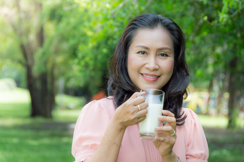 middle-aged woman drinking milk in her garden