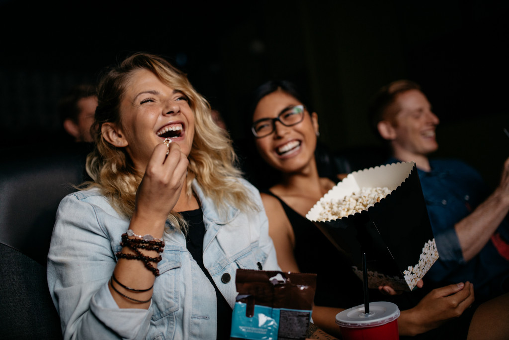 friends watching a movie while eating popcorn in a theater
