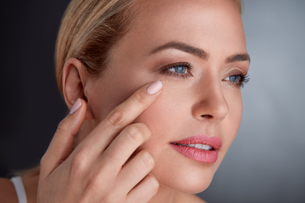 a senior woman with fingertips in the under eye