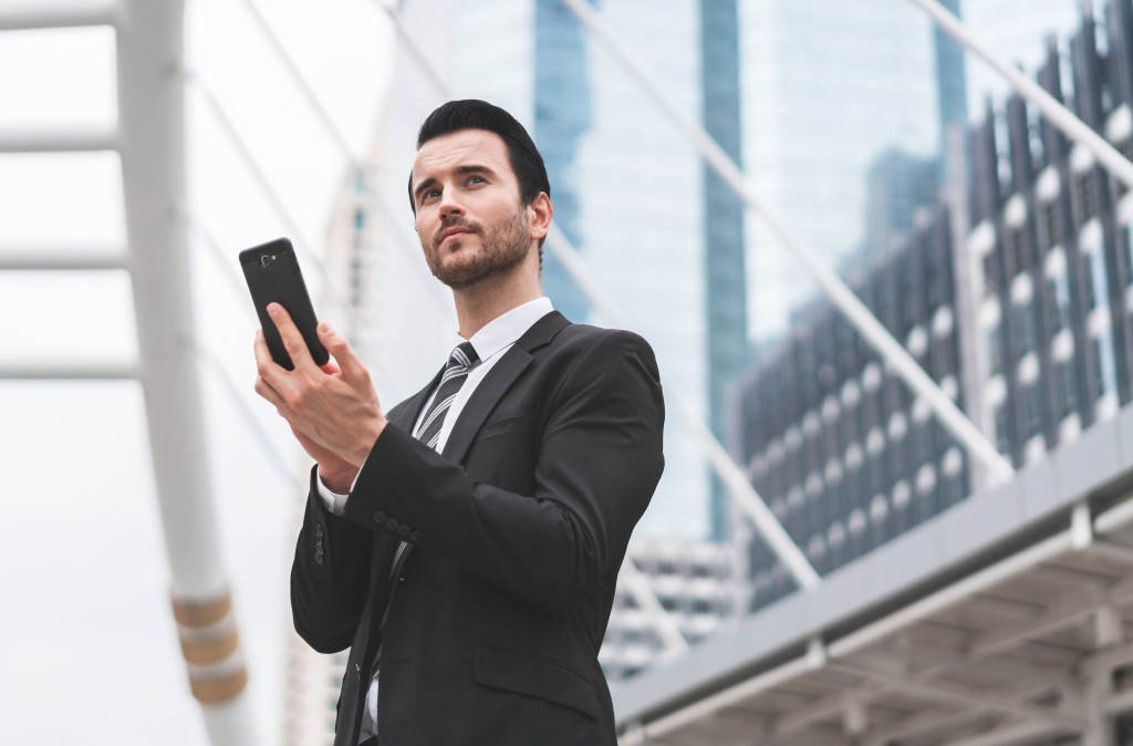 Young businessman wearing a suit while holding a smartphone.