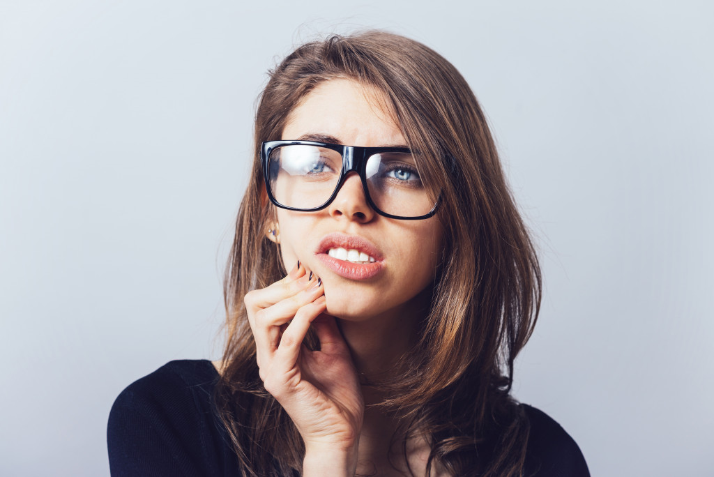 A woman with glasses with gum pain