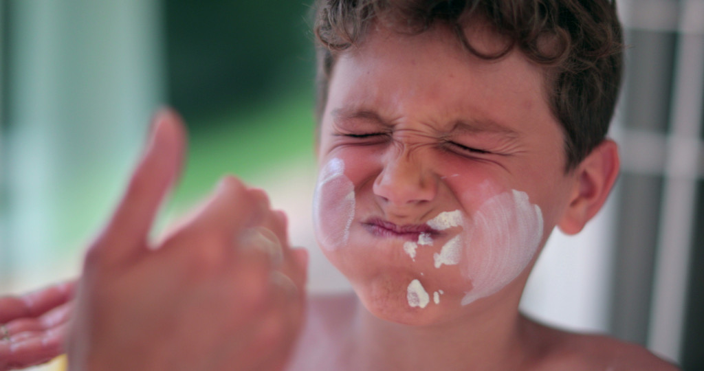 A person applying sunblock on a child's face