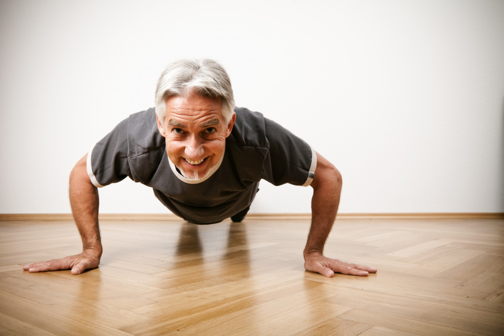 An elderly man doing push ups on the floor