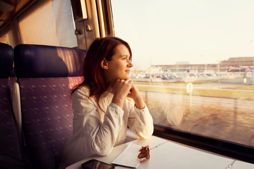 happy female employee in train during sunset meditating