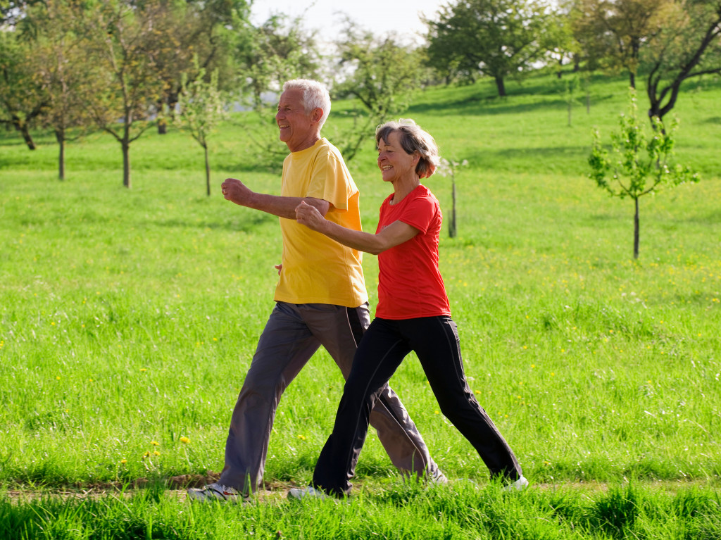 Senior couple going on a power walk across a green field in spring.