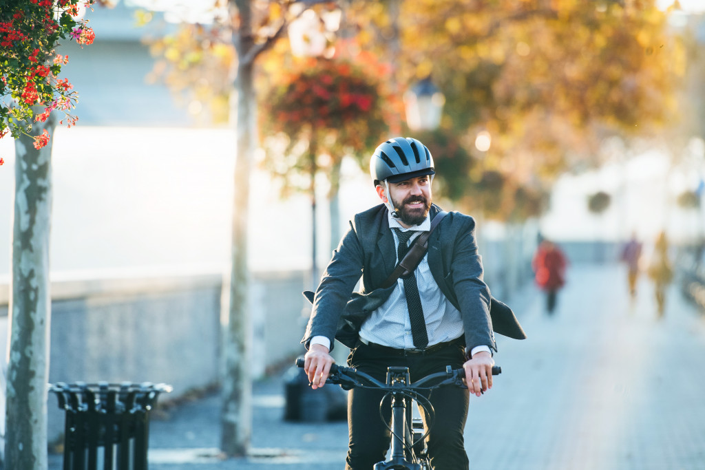 male employee smiling while riding a bike to the office in suit
