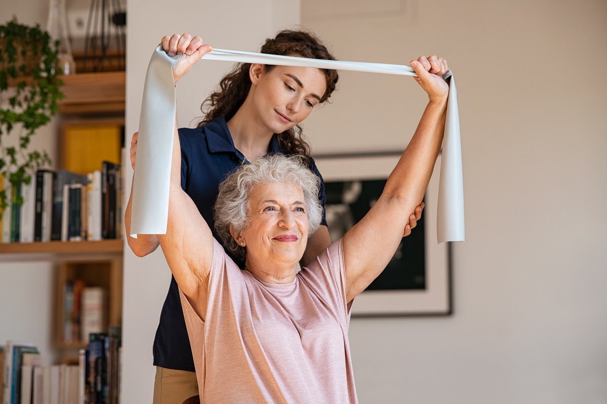A woman assisting a senior in working out