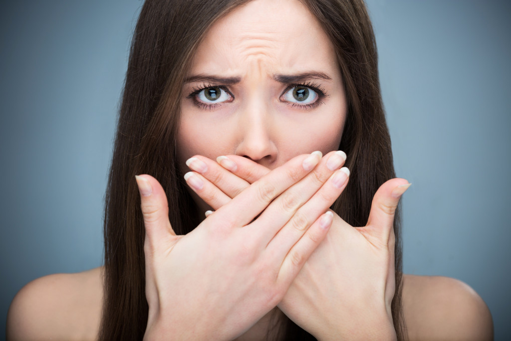 woman covering mouth due to bad breath