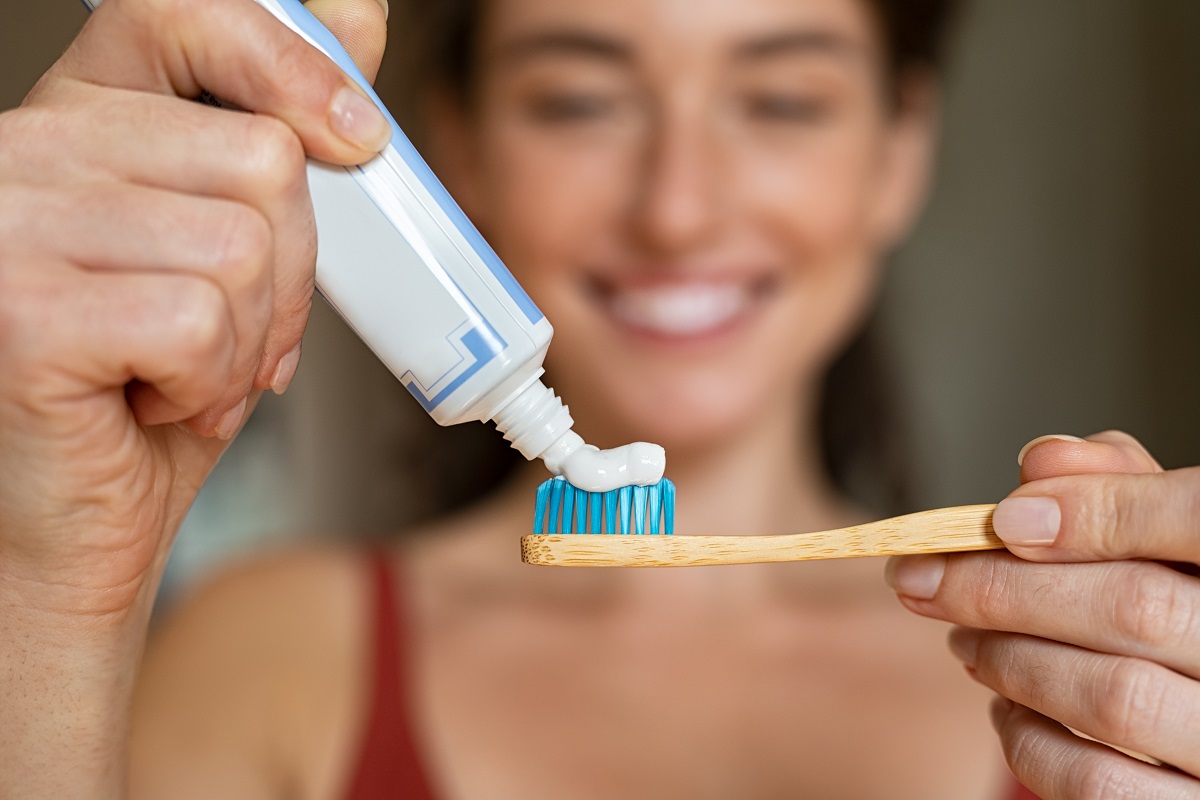 woman applying toothpaste in toothbrush